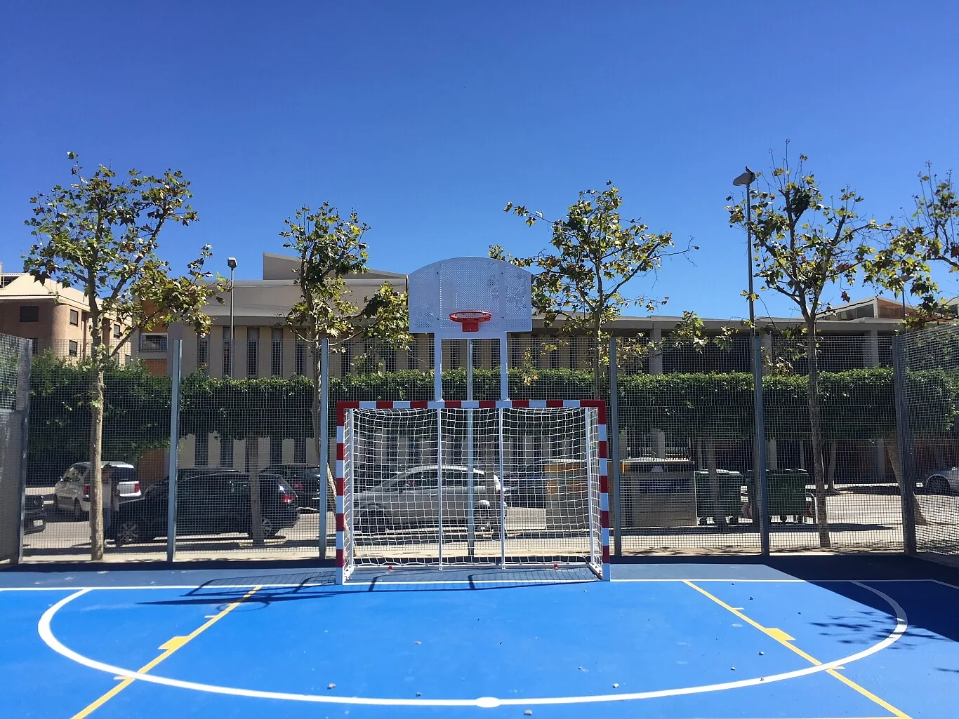 Pista polideportiva exterior azul con canasta y portería en Alaquàs